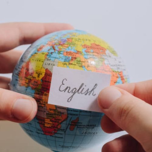 Hand holding notepaper with English wording on model globe